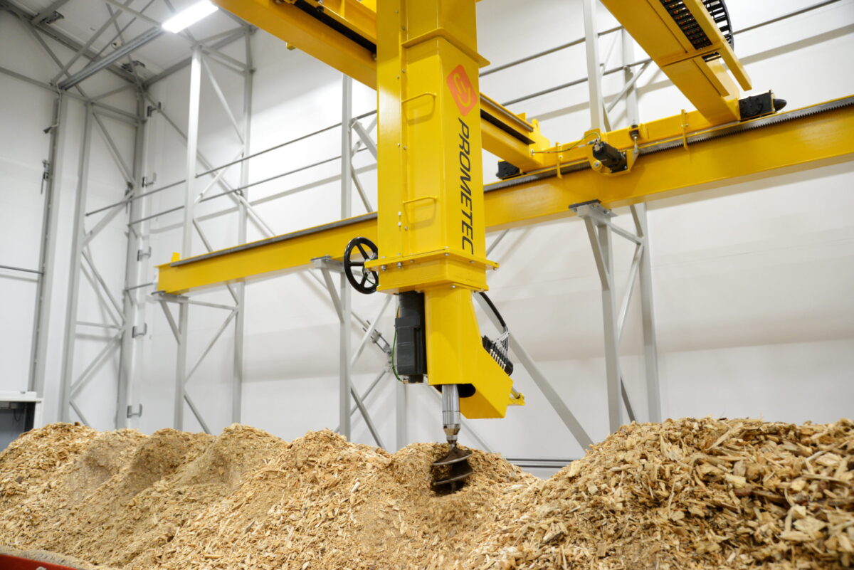 Automated drill sampler collecting a representative biomass fuel sample from a wood chip storage pile.