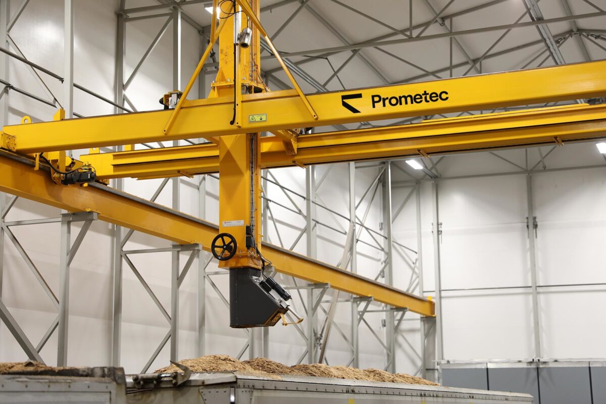 Bridge crane sampling system positioned above biomass fuel load for automated representative sample collection.