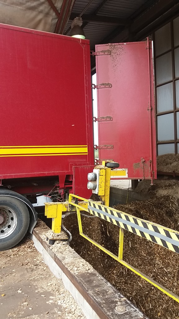 trucks backdoor are open and truck is unloading wood chips to the bunker