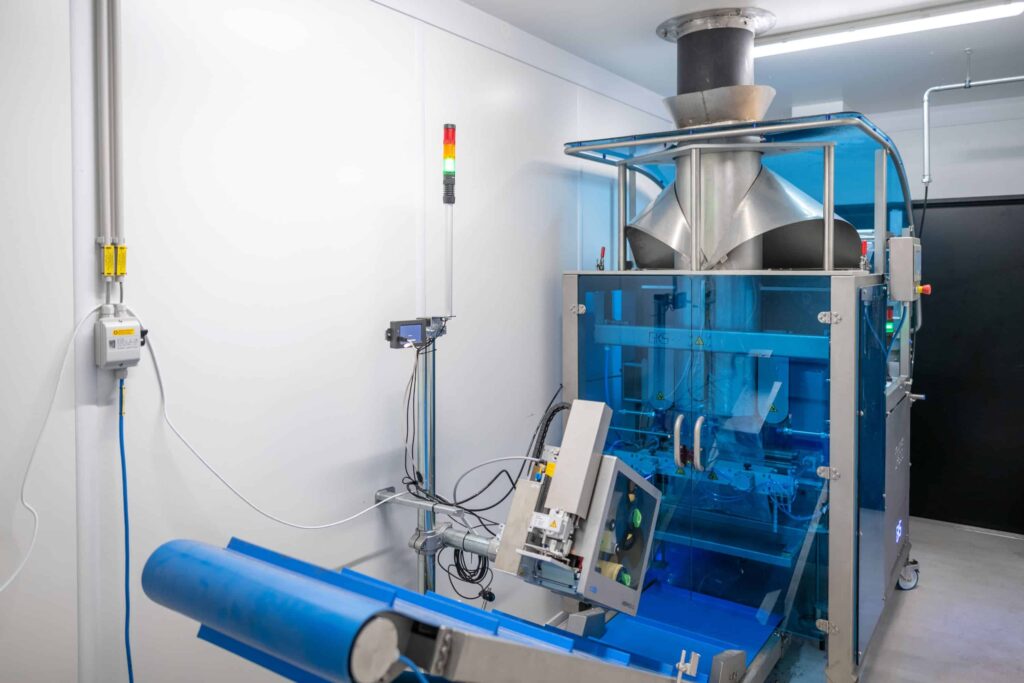 Automated sample bagging machine packaging prepared biomass fuel samples for laboratory analysis and quality control.