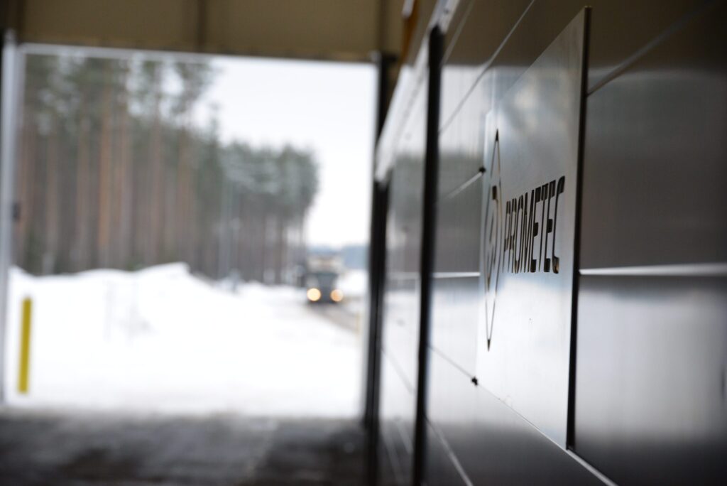 Picture of the prometec's logo which is on the container. a truck is arriving from the background