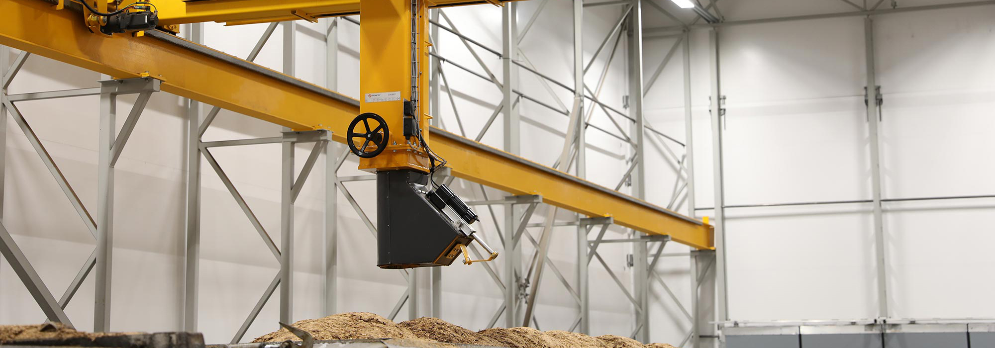 Bridge crane sampling system positioned above biomass fuel load for automated representative sample collection.